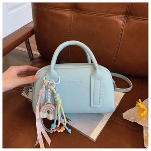 Macro detail of a light blue litchi pattern leather bag with colorful creative charms
