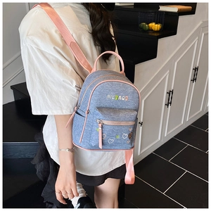 Detail of mini denim backpack featuring pink leather trim and embroidered heart patterns