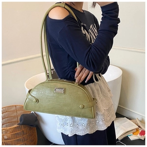 Close-up of green crocodile pattern handbag with silver logo and decorative buckles