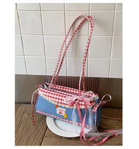 Detail of sweet cherry embroidery with lace trim and bow on blue denim shoulder bag