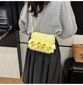 Detail of yellow glossy patent leather crossbody bag with elegant ruffle layers