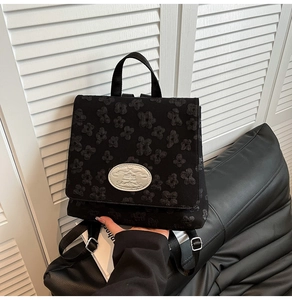 Nahaufnahme eines schwarzen Jacquard-Rucksacks mit Blumenmuster und silbernem Logo-Schild