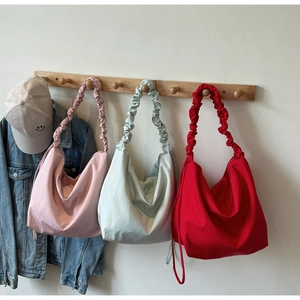Three colorful ruched canvas tote bags hanging on a wall showing stylish pleated straps