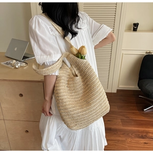 Detail of hand-woven straw shoulder bag with wide strap in a minimalist lifestyle setting