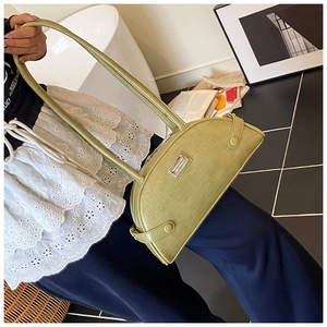 Detail of pistachio green crocodile pattern shoulder bag with metallic brand plate