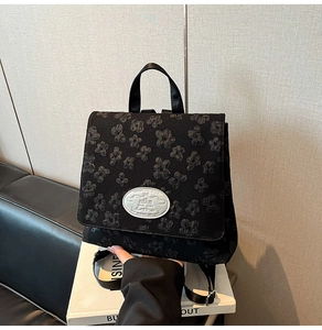 Detail des schwarzen Rucksacks mit Blumenprägung und Mika-Markenlogo-Plakette