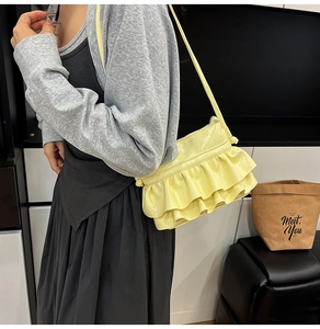 Detail of light yellow ruffle trim shoulder bag with glossy mirror finish texture