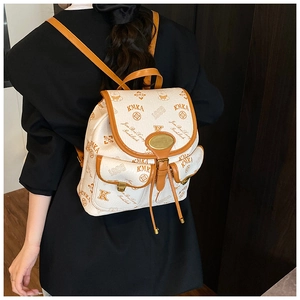 Detail of vintage bucket backpack showing KMKA prints and brown leather trim on model