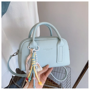 Close-up of light blue pebbled leather handbag with colorful beaded tassel charm