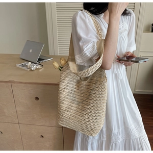 Close-up of beige handmade crochet straw shoulder bag with hollow-out knit details