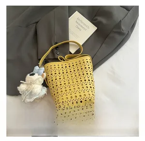 Vue détaillée du sac seau jaune ajouré au laser avec motif géométrique et breloque
