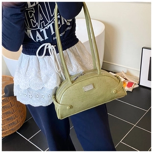 Close-up of green crocodile texture shoulder bag with silver brand plaque detail