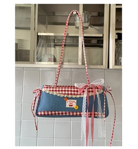 Detailed close-up of denim handbag featuring red plaid trim, lace edges, and cherry embroidery