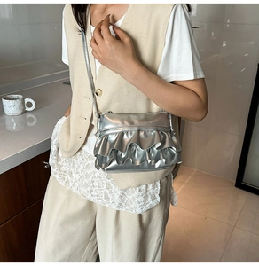 Detail view of silver ruffled small square bag with stylish metallic finish and thin strap