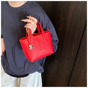 Dettaglio della borsa a secchiello in pelle rossa con motivo litchi e ciondolo argento