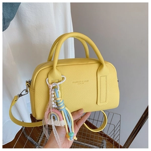 Detail of yellow boston bag with pebble leather and stylish decorative charm