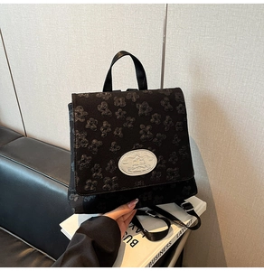 Nahaufnahme der schwarzen Jacquard-Struktur des Rucksacks mit silberner Logo-Plakette