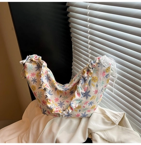 Detailed texture of floral oxford fabric bag with ruffled edges and white lace bow detail