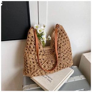 Detail of hand-woven straw tote with hollow geometric patterns and brown leather strap