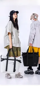 Dual models showing large techwear tote bags with functional buckles in black and beige