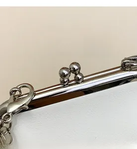 Detail of silver metallic clasp and chain strap for mini crossbody bag with smooth finish