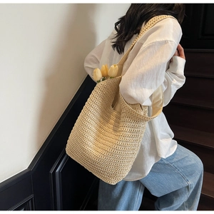 Detail of handmade woven straw tote showing beige texture and large capacity beach style