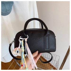 Detail of black pebbled leather handbag with colorful rainbow and ribbon charms