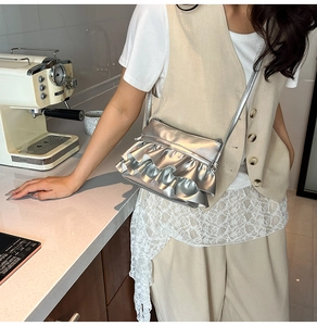 Detail shot of a silver crossbody bag with layered ruffles and sleek metallic texture