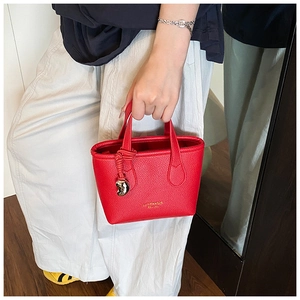 Dettaglio della mini borsa rossa in pelle a grana con logo dorato e ciondolo a cuore