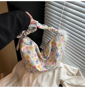 Detail of floral hobo bag with cloud-like pleated handle and delicate lace bow decoration