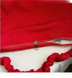 Detail of red canvas tote bag showing smooth silver zipper and striped inner lining