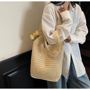 Detailed close-up showing the hollow texture and reinforced handles of a beige woven tote bag