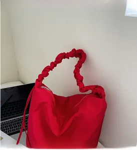 Detail of red pleated nylon tote bag featuring a soft elastic cloud-shaped handle