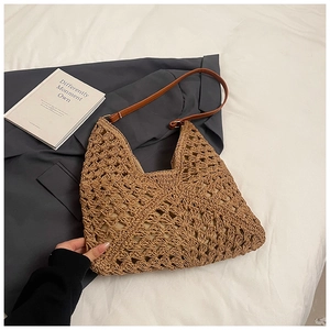 Close-up of hand-woven straw tote bag with intricate crochet pattern and leather strap