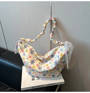 Detail of floral hobo bag featuring ruched cloud handle and white lace bow decoration