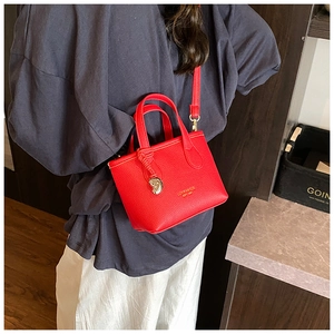 Dettaglio della mini borsa a secchiello rossa con texture a grana e finiture dorate