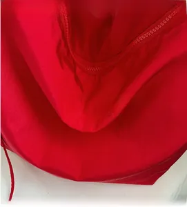 Detail of red canvas tote showing happy vibes embroidery and smooth metal zipper closure