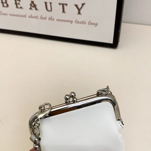 Close-up of the silver metal clasp and leather texture on a white mini crossbody bag