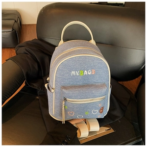 Detail of light blue denim mini backpack with MY BAG embroidery and white leather trim