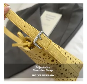 Détail de la bandoulière réglable et du motif ajouré au laser sur le sac seau jaune