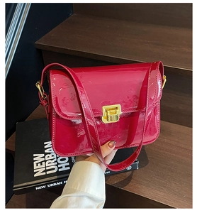 Detail of red patent leather shoulder bag with gold metal buckle and glossy finish