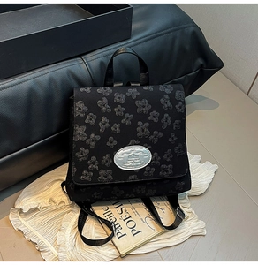 Detail eines schwarzen Rucksacks mit 3D-Blumenstickerei und ovalem Metall-Logo-Schild