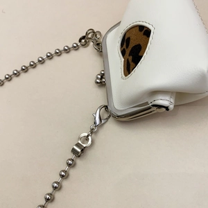 Detail of white leather mini coin purse with leopard heart patch and silver chain