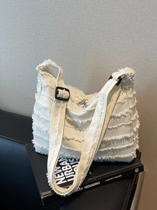 Cream canvas tote bag with layered fringe and adjustable strap for urban commute style