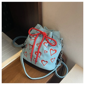 Détail du sac seau en velours côtelé bleu clair avec broderies de cœurs rouges et cordons