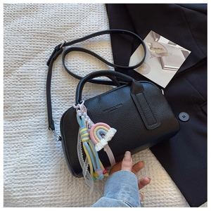 Detail of black Boston bag with lychee texture leather and colorful rainbow tassel charm
