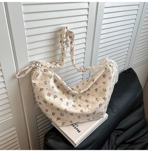 Close-up of a floral oxford bag with pleated strap and delicate white lace trim detail