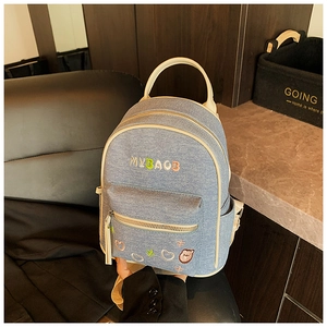 Detail of light blue denim backpack featuring colorful MYBAGB embroidery and heart icons