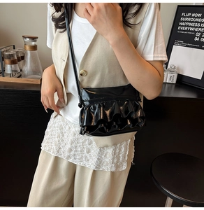 Chic black glossy balletcore crossbody bag with ruffled layer detail on model