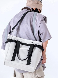 White high-capacity crossbody tote bag with black nylon straps shown on model